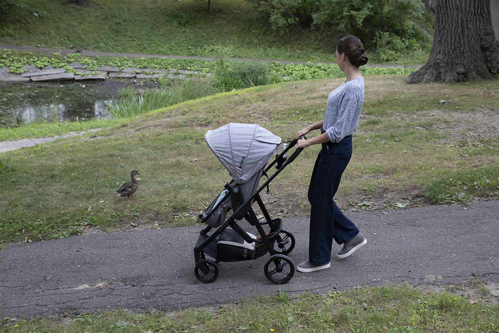 Woman pushing stroller in park before retouching